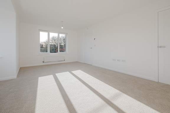 A white room with a carpet and a window.