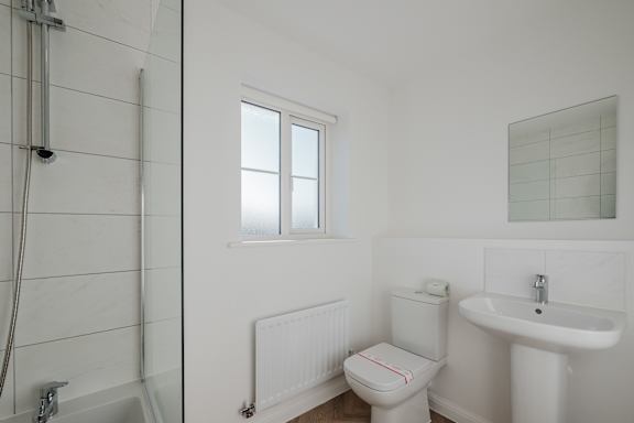 A white bathroom with a toilet, sink, and shower.