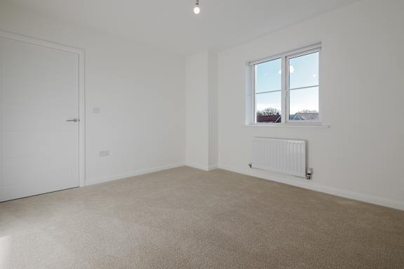 A room with a white door, a window, and a radiator.