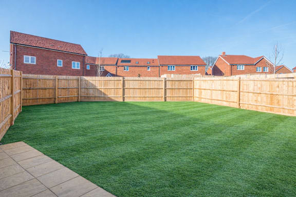 A backyard with a wooden fence and a green lawn.