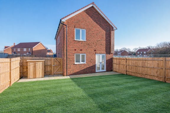 A red brick house with a green lawn in front.