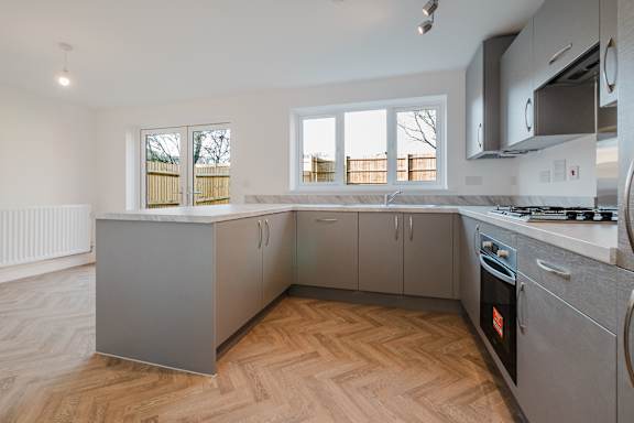 A modern kitchen with wooden flooring and stainless steel appliances.