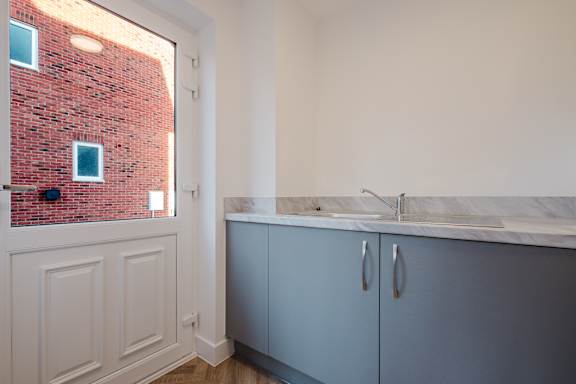 A kitchen with a red brick wall and white cabinets.