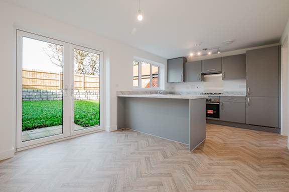 A kitchen with a herringbone patterned floor and a countertop that extends to a window.