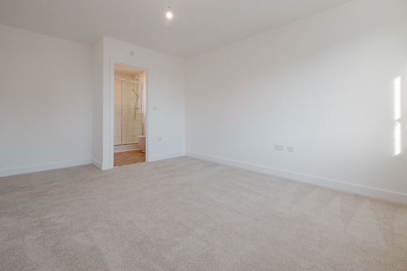 A large, empty room with a carpeted floor and a doorway leading to another room.