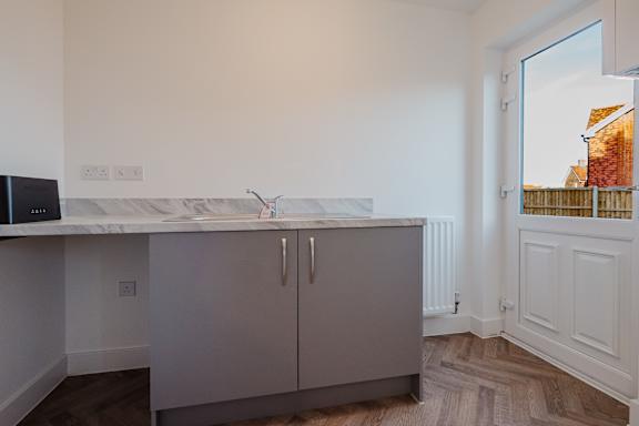A kitchen with a marble countertop and grey cabinets.