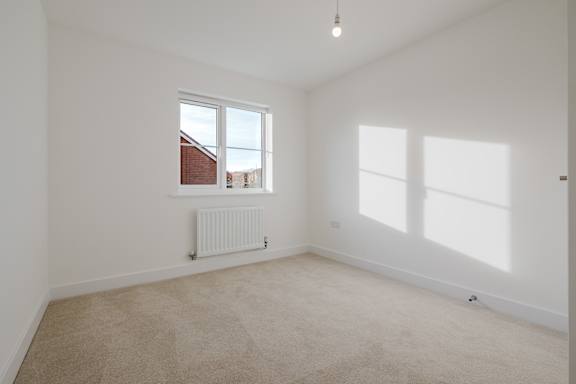 A room with a carpeted floor and a window.