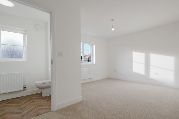 A white room with a toilet and a window.