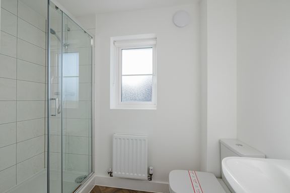A white bathroom with a glass shower door and a white tub.