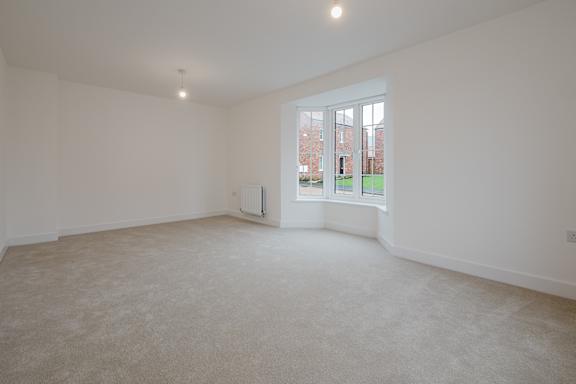 A large empty room with a window overlooking a green lawn.