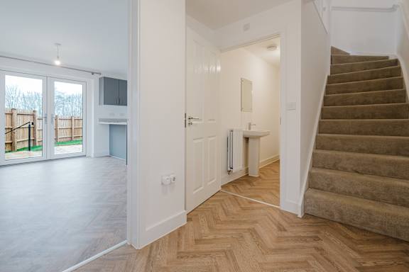 A staircase with a carpeted runner leads up to a landing with a white door and a small table.