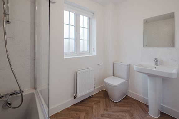 A white bathroom with a toilet, sink, and shower.