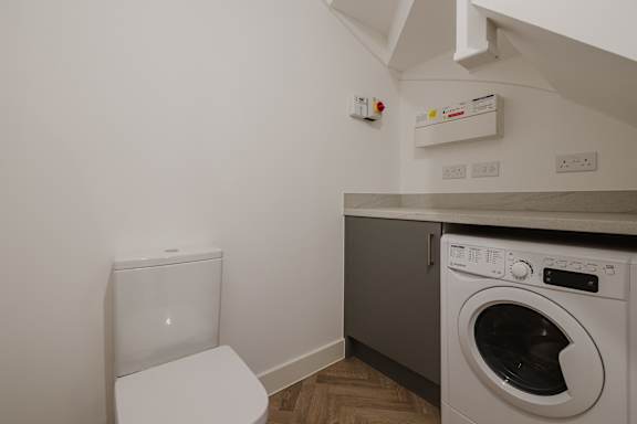 A white toilet sits next to a washing machine in a small room.