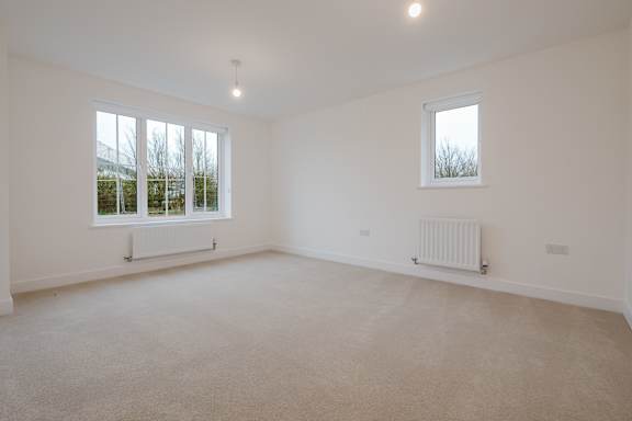 A white room with a window and a radiator on the wall.