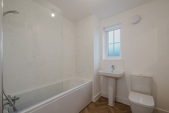 A white bathroom with a tub, sink, and toilet.