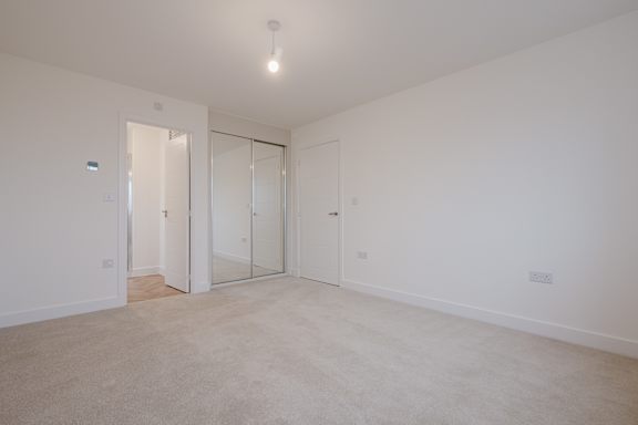 A large empty room with a carpeted floor and white walls.