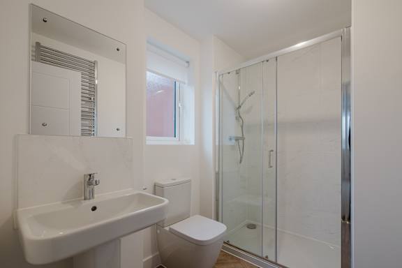 A white bathroom with a sink, toilet, and shower.
