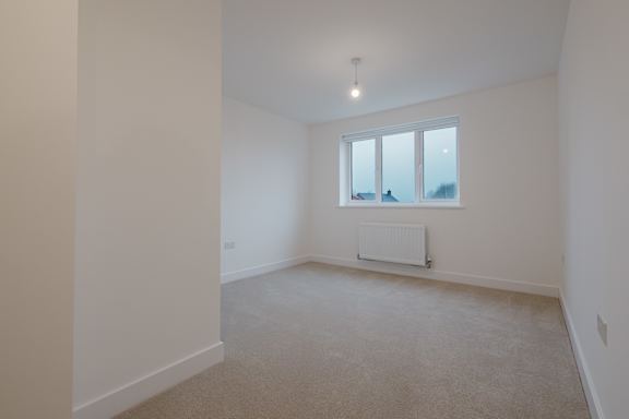 A room with a window and a radiator on the floor.