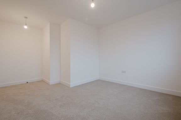 A large empty room with carpeted floor and white walls.
