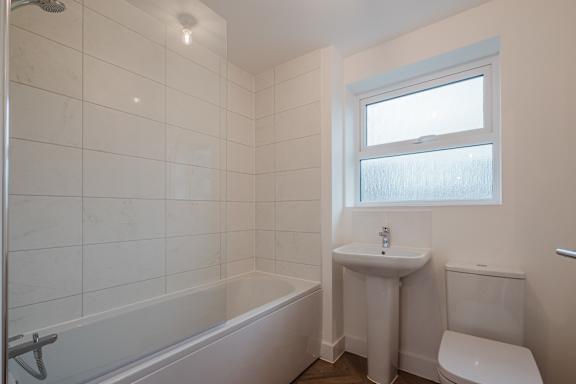 A white bathroom with a tub, sink, and toilet.