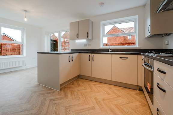 A kitchen with wooden flooring and white walls.