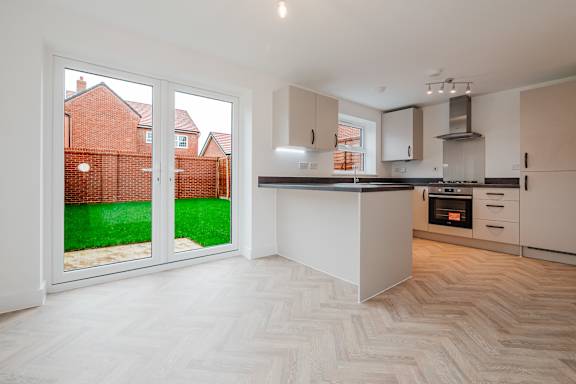 A modern kitchen with a wooden floor and white walls.
