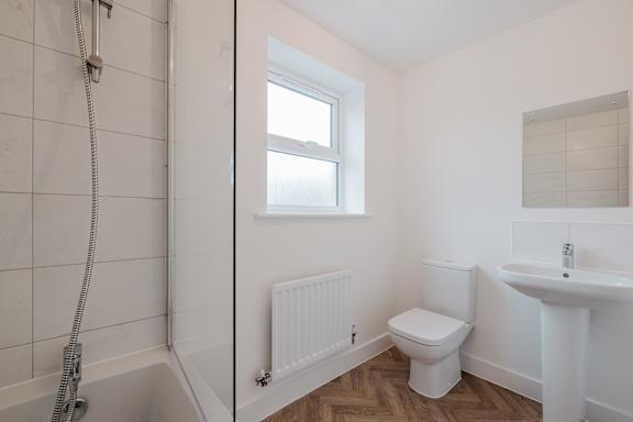A white bathroom with a toilet, sink, and window.