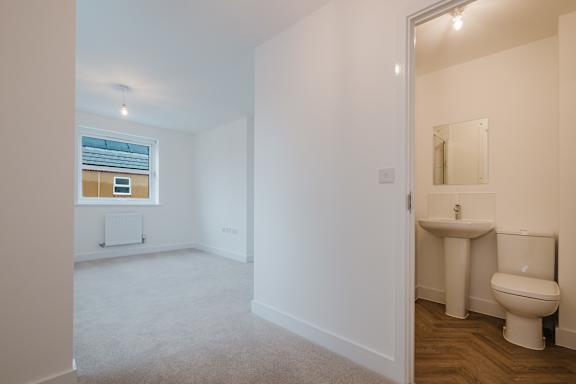 A white bathroom with a toilet, sink, and window.