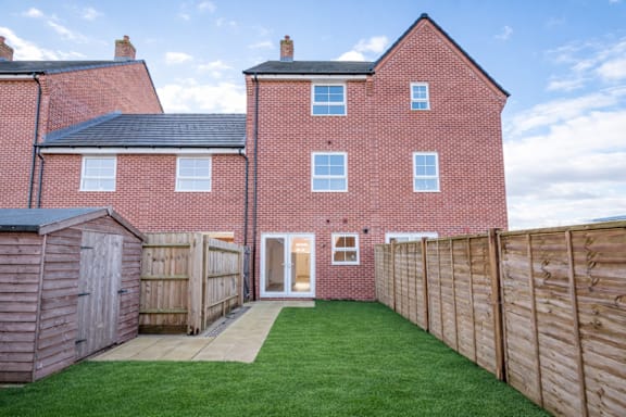 A red brick house with a wooden fence and a green lawn.