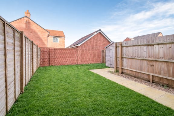 A backyard with a wooden fence and a green lawn.