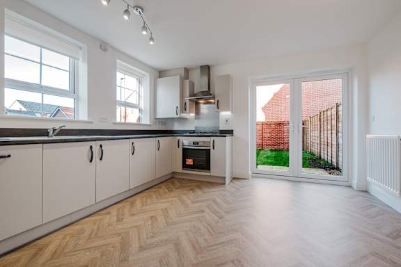 A kitchen with a wooden floor and white cabinets.