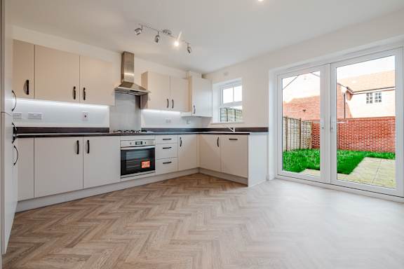 A kitchen with a wooden floor and white cabinets.