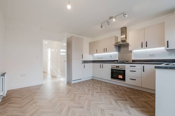 A modern kitchen with a wooden floor and white cabinets.