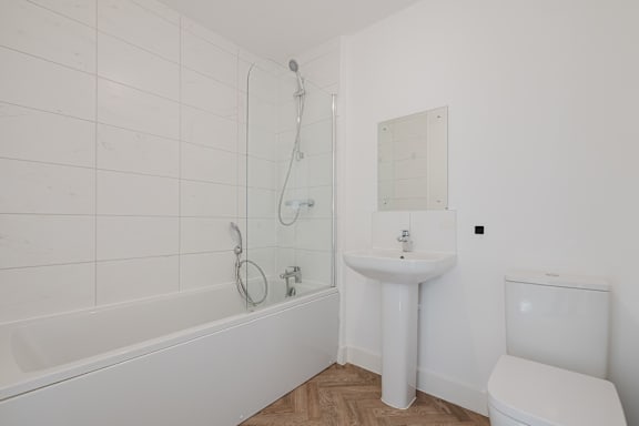 A white bathroom with a tub, sink, and toilet.