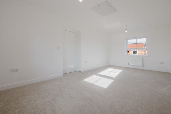 A large empty room with a window showing a building outside.