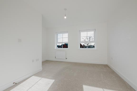 A room with two windows and a radiator on the wall.