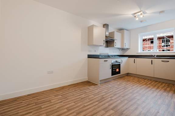 A kitchen with wooden floors and white walls.