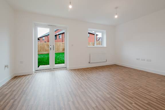 A room with a wooden floor and a window overlooking a backyard.