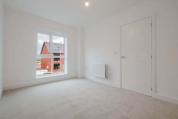 A room with a white door, a window, and a radiator.