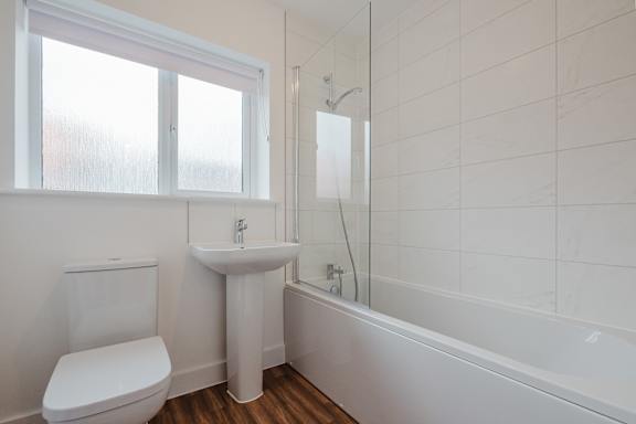 A white bathroom with a toilet, sink, and bathtub.
