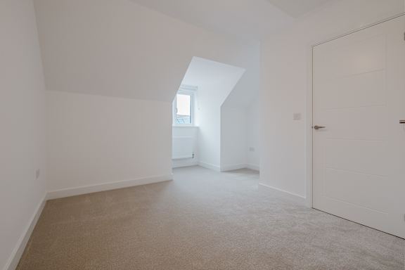 A spacious room with a carpeted floor and a skylight.