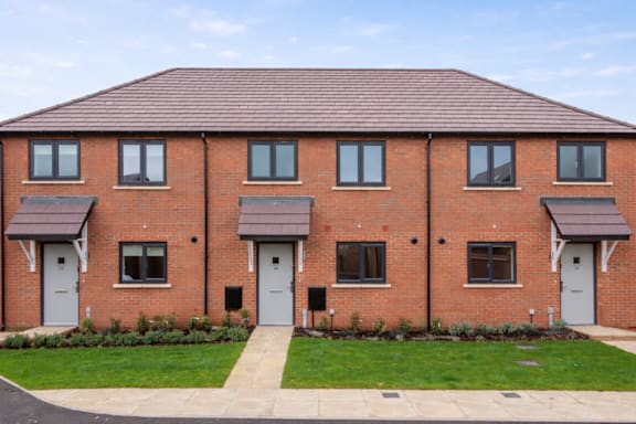 A red brick house with a grey roof and grey doors.