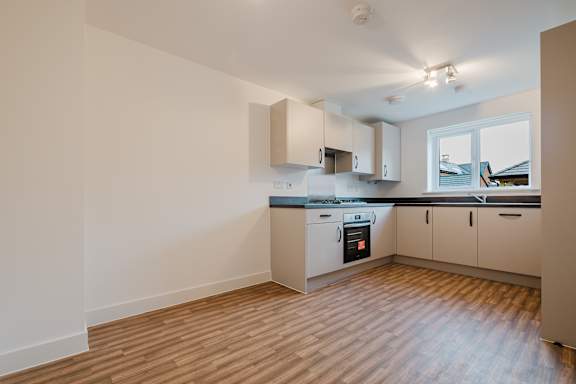 A kitchen with wooden floors and white walls.