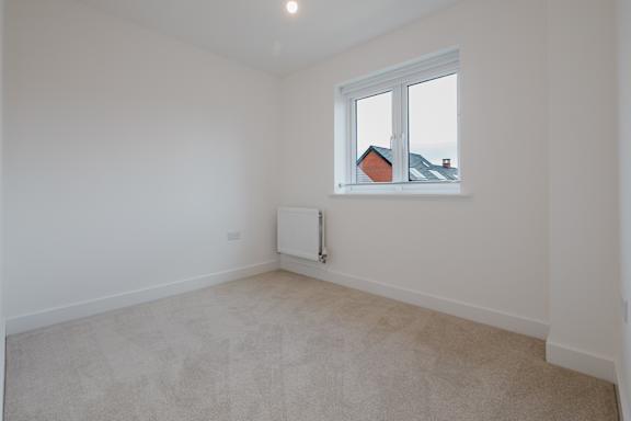 A white room with a window and a radiator on the wall.