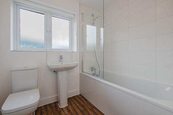 A white bathroom with a toilet, sink, and bathtub.