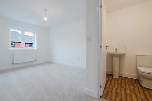 A white bathroom with a toilet, sink, and window.