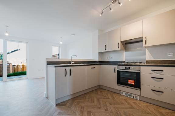 A modern kitchen with wooden flooring and stainless steel appliances.