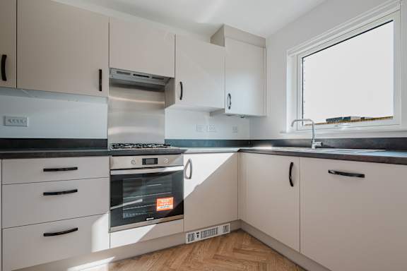 A modern kitchen with white cabinets and a stainless steel oven.
