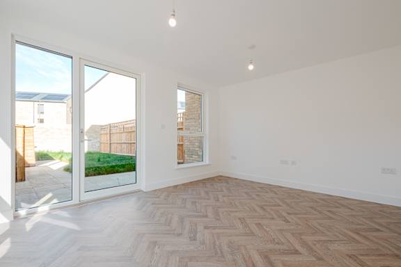 A room with a herringbone parquet floor and a window overlooking a garden.