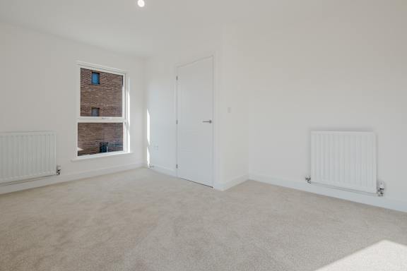 A room with a window, a door, and a radiator.